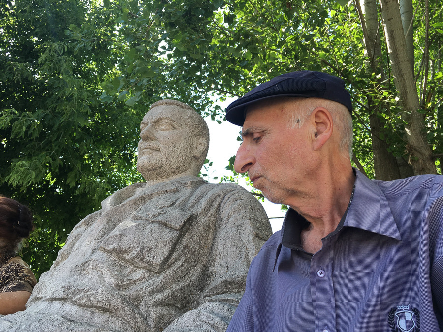 A man sitting next to a statue-memorial of Armenia’s late Defense Minister and later Prime Minister Vazgen Sargsyan in Shushi. (Photo: Souren Papazian)